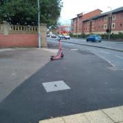 A Voi scooter parked in the middle of a large area of pavement
